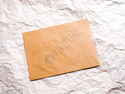 牛皮纸信封放在皱巴的纸上背景图片