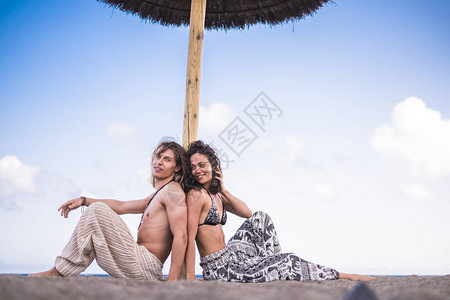 年轻夫妇坐在蓝天空背景的雨伞图片