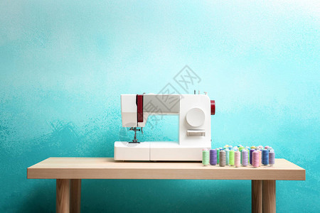 有色背景的桌子上有线的缝纫机图片