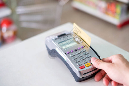在超市付款终端上用打刷信用卡的手图片