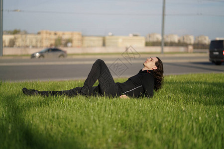 一名青年男子坐在大路附近的草地上图片