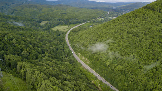 汽车沿着蜿蜒的山口公路穿过俄罗斯索契森林的空中库存照片图片