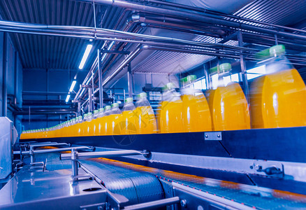 饮料厂内部装有果汁或水瓶的输送机现代设备背景图片