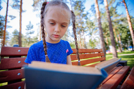 小姑娘在户外看书花园里的孩子拿着书回图片