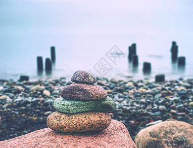 象征禅宗和谐平衡卵石的头金字塔背景是平静的海洋用于冥图片