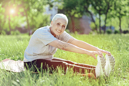 积极善良活跃的老年妇女在公园运动时试图触摸她的脚图片