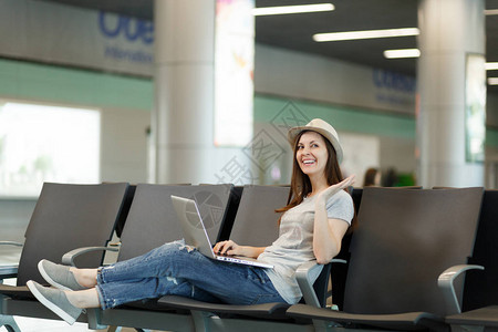 年轻的笑着旅行的旅游妇女坐在笔记本电脑上工作图片