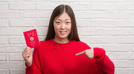 持有日本护照的青年女子在砖墙上翻墙图片