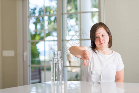 家里的唐氏综合症女带着愤怒的脸喝着饮用水消极迹象显示不喜欢低拇图片