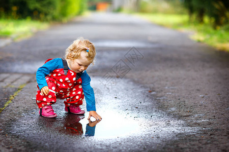 蹒跚学步的小女孩穿着雨靴和裤子图片