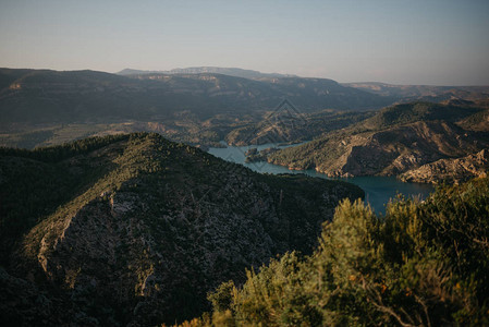 西班牙日落时绿林覆盖着古代山谷底部的翡翠河在图片