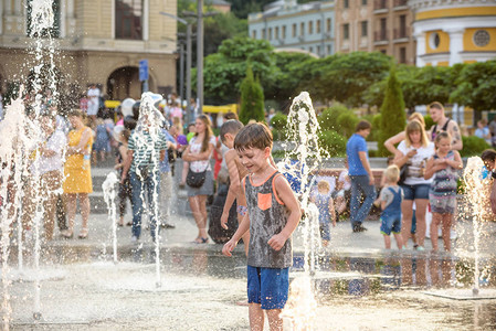 快乐的孩子们在炎热的夏日在城市喷泉玩耍父母与他们的孩子积极的家庭休图片