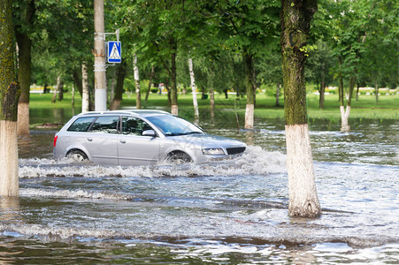 汽车通过横行道在城市中一条淹水图片