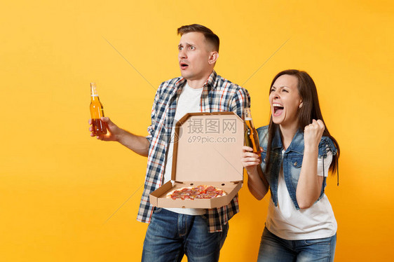 年轻男体育球迷欢呼支持团队把啤酒瓶意大利披萨装在纸板小盒子里赢家的手势是尖叫声孤立在黄色背景上运动家庭图片