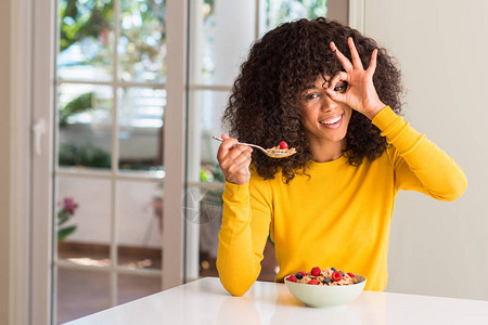 非裔美国妇女吃麦片草莓和蓝莓图片