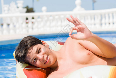 度假时在海滩边游泳池垫上子的小孩用手指做好手势图片