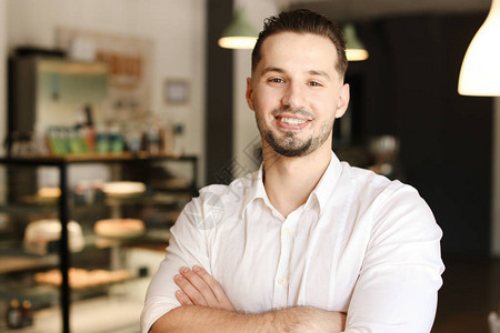 年轻的男微笑管理者站在咖啡馆里商业和成功的概图片