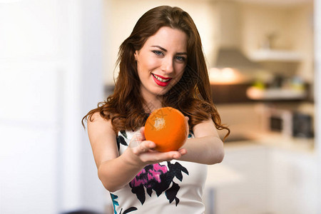 快乐的美丽年轻女孩拿着橙子在背景图片