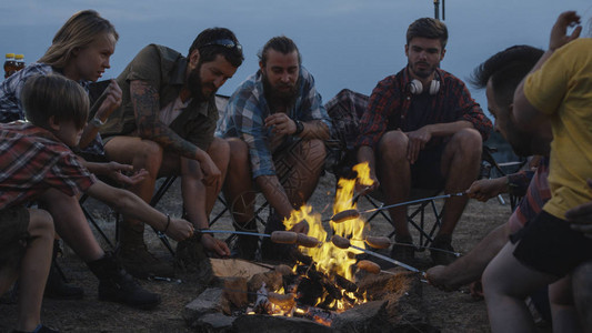 成年人和孩子们聚集在露营地的篝火旁图片