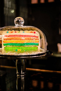 彩虹层蛋糕在玻璃铃穹顶下蛋糕摊甜点储背景图片