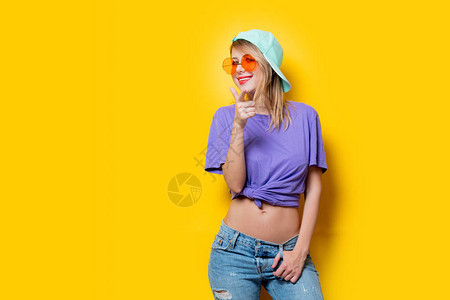 有橙色眼镜和黄色背景帽子的年轻时装女孩图片