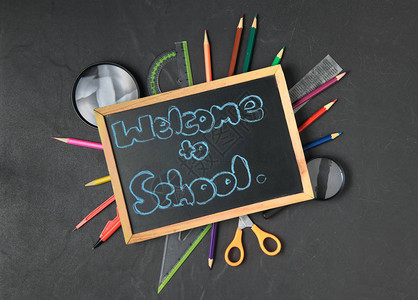 黑纸板欢迎上学和学校用品的粉笔回图片