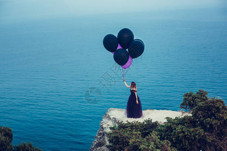 穿着深色衣服的美丽年轻时尚女士拿着气球对图片