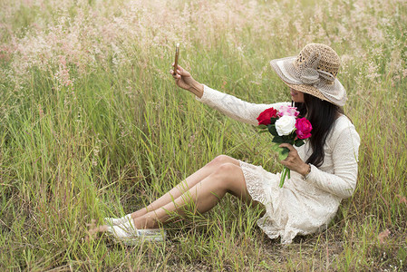 一个微笑的年轻美女戴着一束玫瑰花戴帽子的肖像图片素材