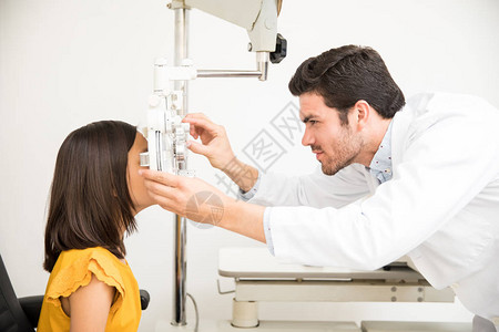 在光学商店接受青年验光师进行视力测试的小女图片