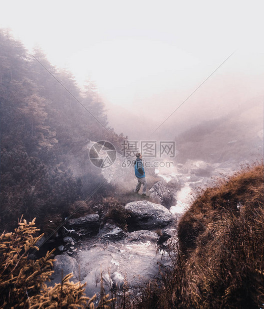 一个人在雾天站在山区河流附近图片