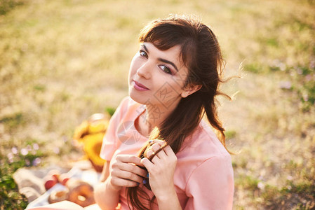 一个女孩坐在草地上野餐时带图片
