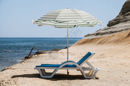 两张蓝色的甲板椅子和一张沙滩伞还有绿色条纹在马耳他一个图片