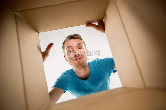 男人微笑拆包打开纸箱和看里面包裹送货惊喜礼物生图片