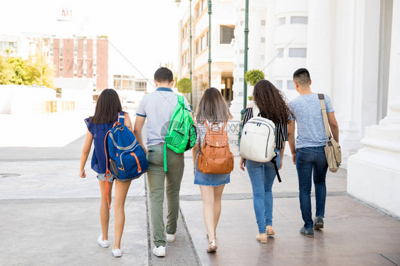 5名十几岁的男孩和女孩带着书包在市街上走出图片