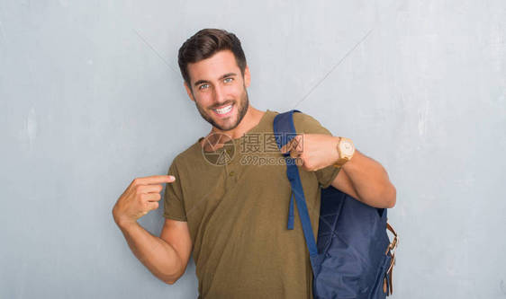 英俊的旅游年轻人站在灰色的垃圾墙上图片