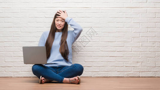 年轻的女人坐在砖墙上的地板上图片