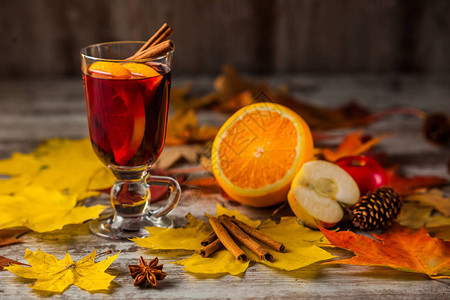 热红酒在秋天的背景上玻璃杯中的橙色肉桂红葡萄酒精秋叶黄红色在木图片