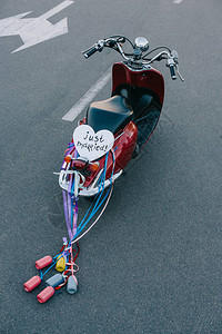 带有彩色罐头丝带和刚结婚心形符号的老式轻便摩托车的后视图图片