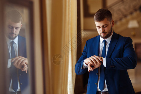 新郎在婚礼燕尾服微笑着在酒店大厅里等待新娘有钱的新郎在婚礼当天穿着服装和领结的优雅新郎穿着西装的图片