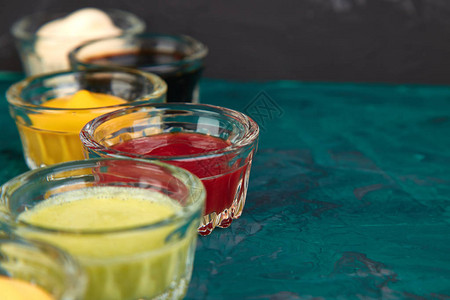 一套不同的酱汁在绿色背景的小碗里调味番茄酱芥末蛋黄酱图片
