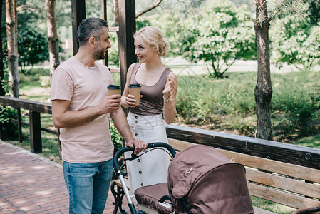 开心的父母拿着咖啡在公园的婴儿车图片