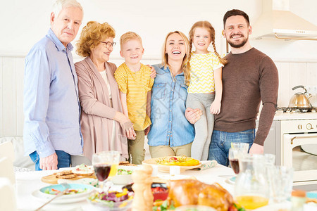 两代六人家庭在家中摆姿势站在节日晚宴桌图片