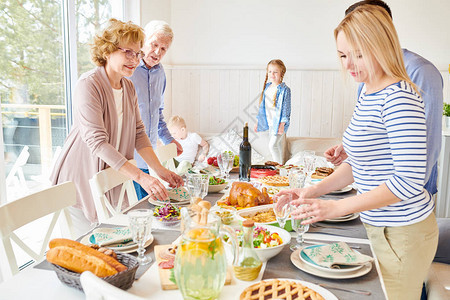 幸福的两代家庭在现代阳光明媚的公寓里一起享用节日餐桌图片