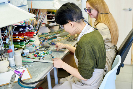 两位现代女艺术家在玻璃工作室制作精美手工珠宝子时用玻璃塑图片