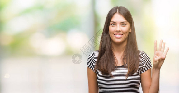 年轻美丽的西班牙女神露面用四号手指举起手微笑着自信背景图片