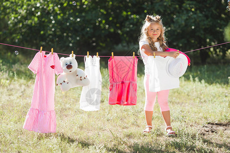 可爱的小女孩在户外晾衣服背景图片