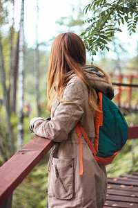 红长头发的女孩旅行者站在森林桥上图片