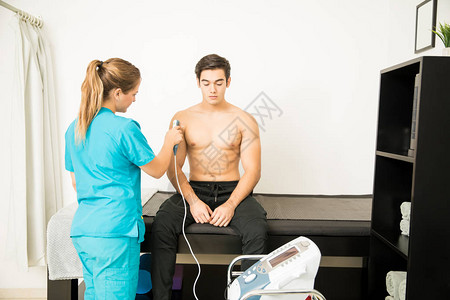 接受诊所理疗师电动超声波肩部按摩的无图片