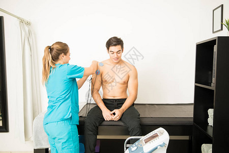 年轻理疗师让男病人在诊所肩膀图片