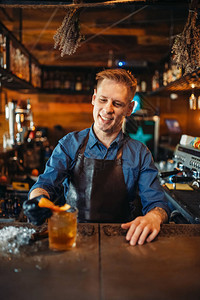 围裙的男酒保在酒吧柜台工作酒精饮料的制备酒保职图片